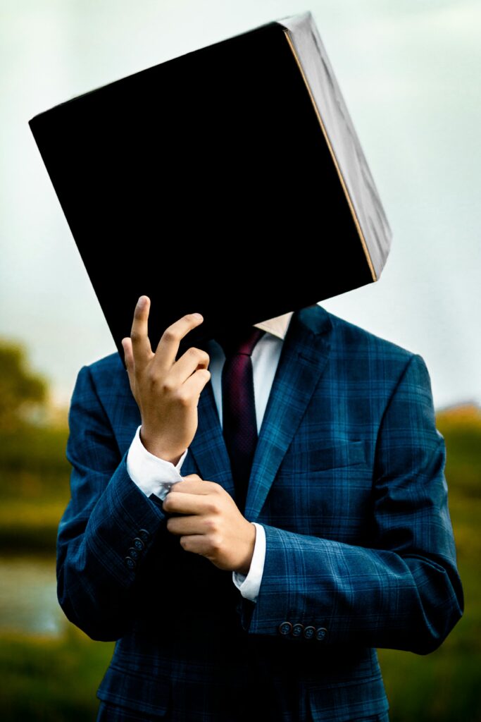 Globally_ Services_2 Mysterious portrait of a man in a blue suit with a box on his head, standing outdoors.