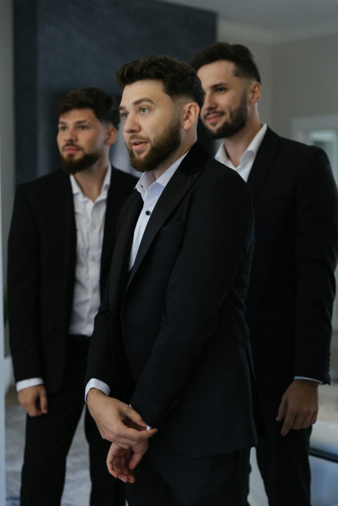 pexels-photo-27687913-27687913 Three men wearing black suits, standing indoors, exuding professionalism.