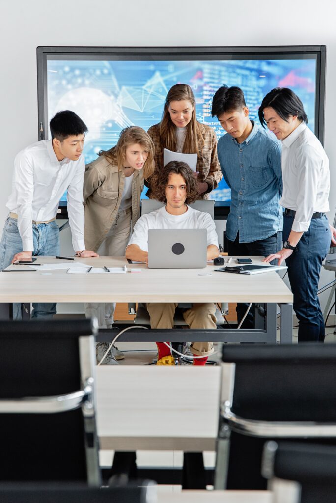 pexels-photo-7988215-7988215 A diverse group of professionals engaged in teamwork around a laptop in a contemporary office setting.